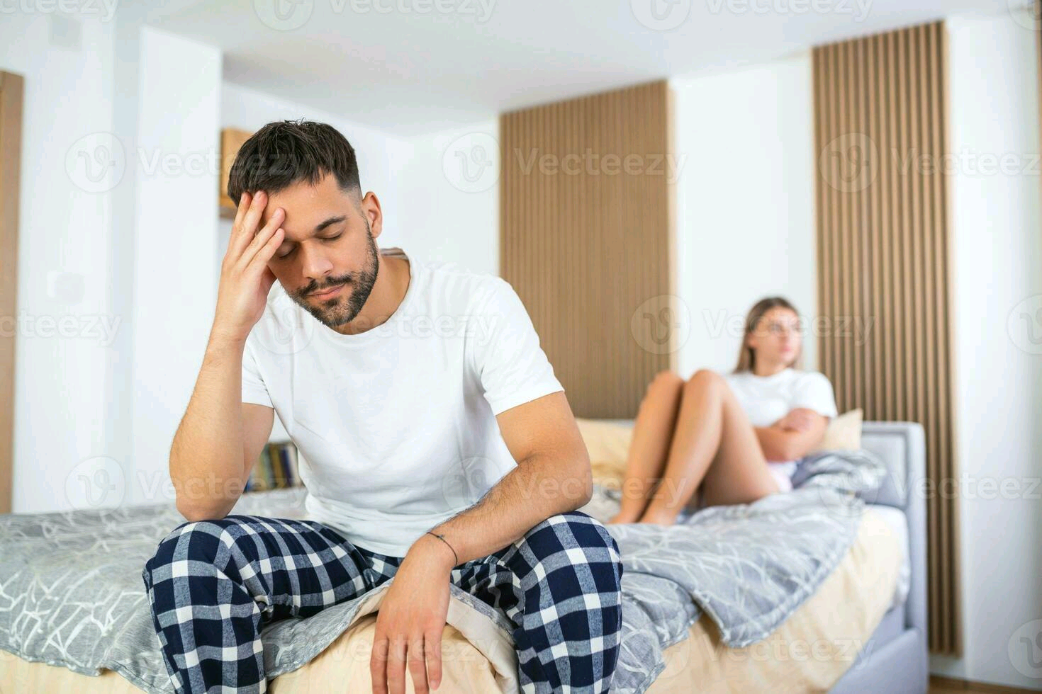 Beautiful girl and a frustrated man sitting in bed and not looking at each other upset couple ignoring each other worried man in tension at bed young couple angry with each other after a fight photo