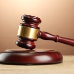 Wooden gavel on wooden table, on brown background